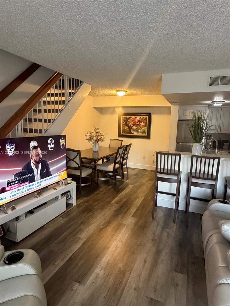 An open-concept living and dining area features wood-look flooring, a staircase, and a kitchen island — 675 NW 85th Ct # 207, Miami FL 33126, MIAMI, FL