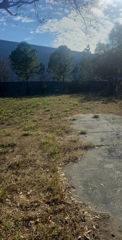 A grassy lot features a concrete slab in the foreground and a fenced perimeter — LINCOLN COURT, AUBURNDALE, FL