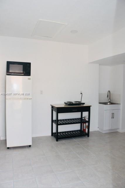 A small kitchen area features a white refrigerator, a black utility cart, and a sink — MARGATE, FL