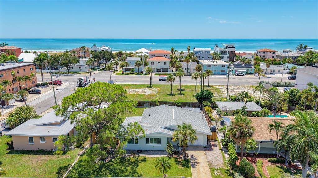 An aerial view shows a coastal neighborhood with houses, palm trees, and the ocean beyond — 3602 CASABLANCA AVENUE, ST PETE BEACH, FL