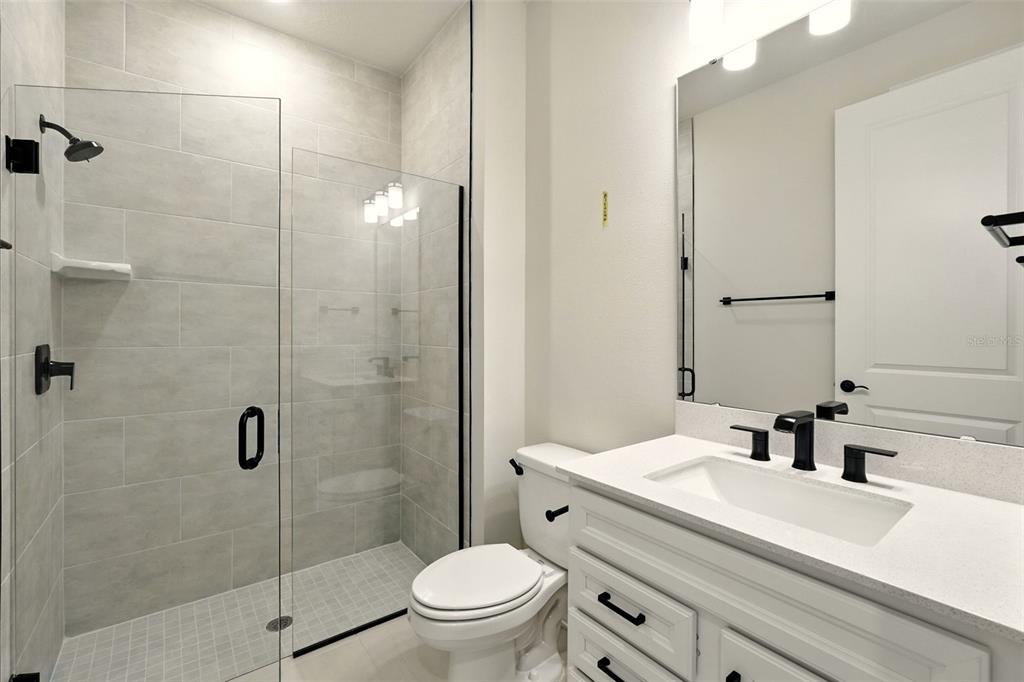 A modern bathroom features a glass-enclosed walk-in shower, a white vanity, and black hardware — 276 SUMMER PINE STREET, WINTER GARDEN, FL