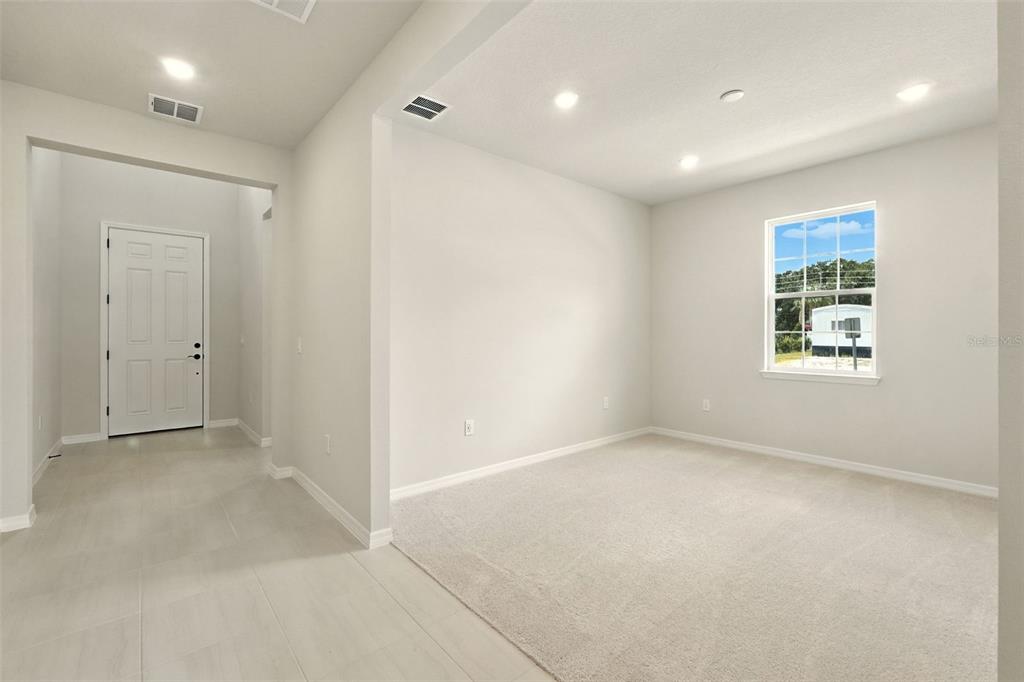 A room with beige carpet and light-colored walls features a window and an adjacent entryway — 276 SUMMER PINE STREET, WINTER GARDEN, FL