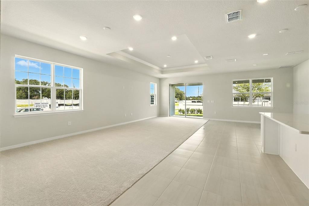 A bright, open-concept living area features neutral carpeting, tile flooring, and a tray ceiling — 276 SUMMER PINE STREET, WINTER GARDEN, FL