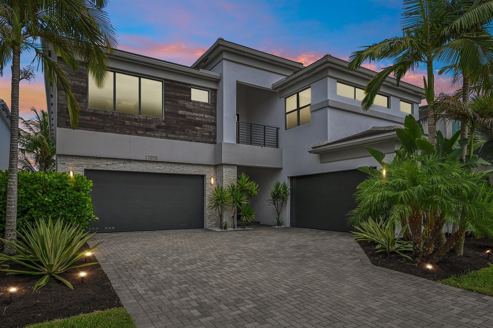 A modern two-story house features a paved driveway, two garages, and palm trees at dusk — 17070 Rainbow Falls Trail, Boca Raton FL 33496, BOCA RATON, FL