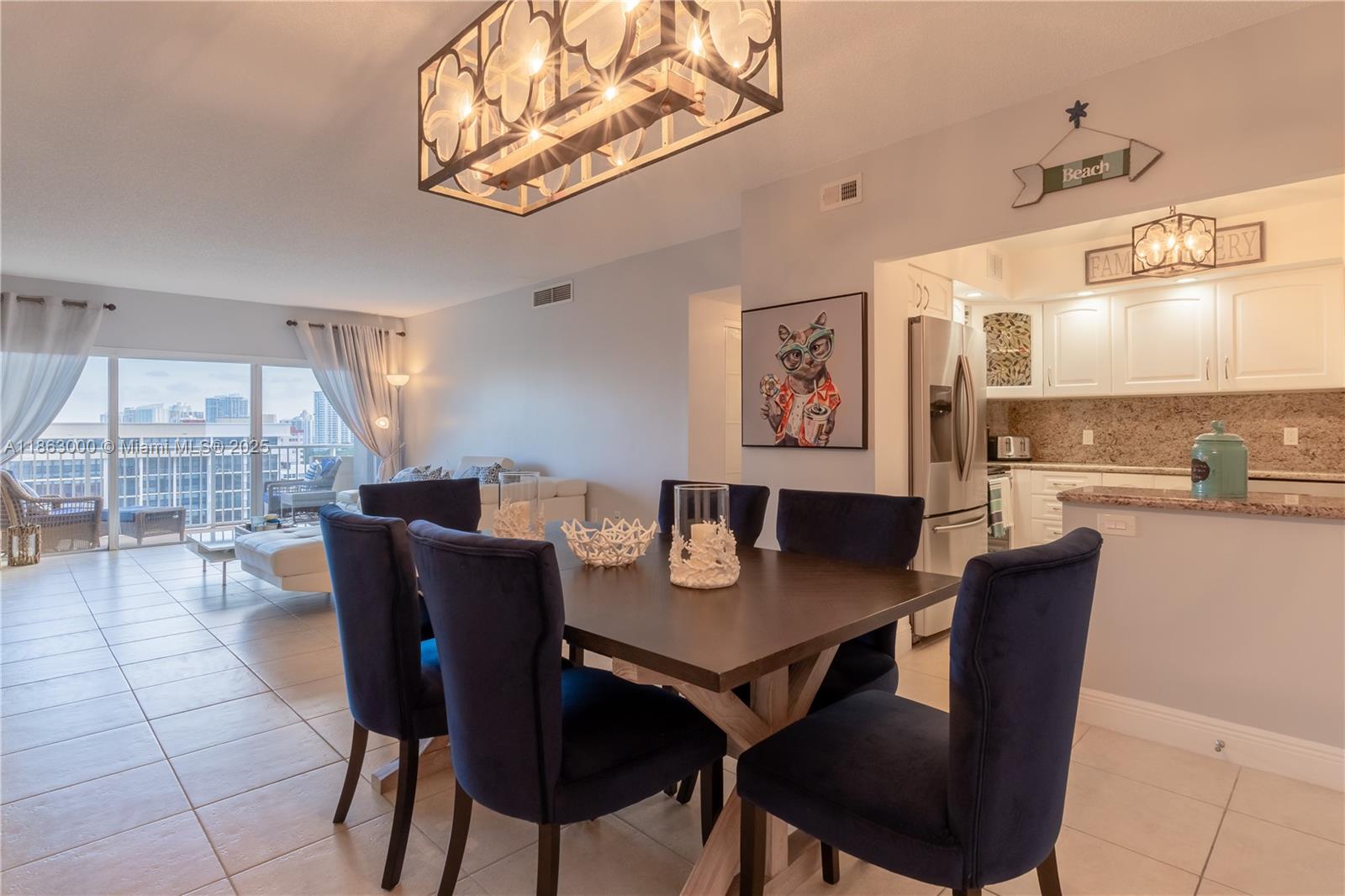 A dining area with dark blue chairs and a wooden table sits near a kitchen — 1985 S Ocean Dr # 15G, Hallandale Beach FL 33009, HALLANDALE BEACH, FL
