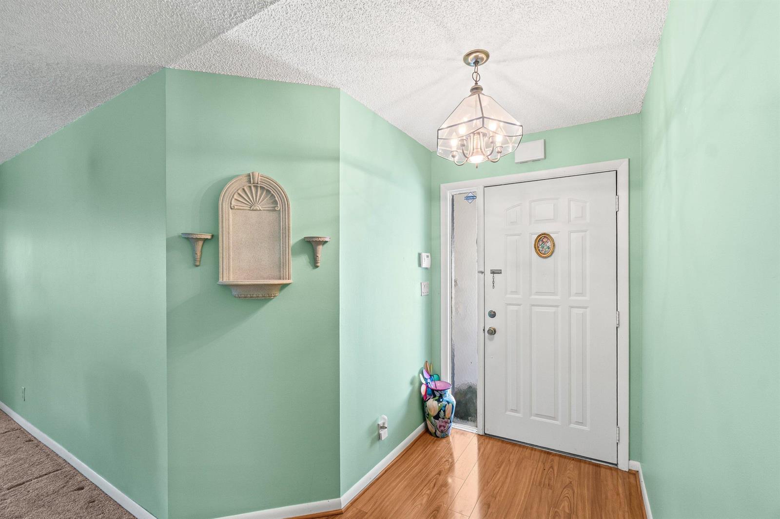 An entryway with mint green walls, wood flooring, a white door, and a decorative wall niche — 69 King Fisher Way, Boynton Beach FL 33436, BOYNTON BEACH, FL