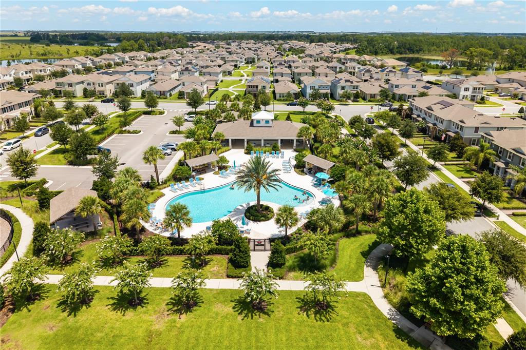 An aerial view shows a community swimming pool and clubhouse surrounded by suburban residential homes — 16161 MANGROVE ROAD, WINTER GARDEN, FL