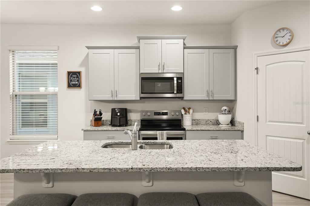 A kitchen features light gray cabinets, granite countertops, a central island, and stainless steel appliances — 16161 MANGROVE ROAD, WINTER GARDEN, FL