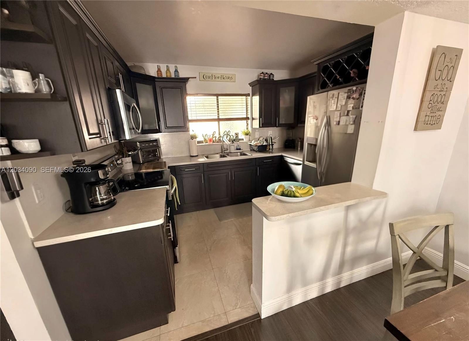 A kitchen features dark wood cabinets, light countertops, stainless steel appliances, and a breakfast bar — 8520 SW 133rd Ave Rd # 424, Miami FL 33183, MIAMI, FL