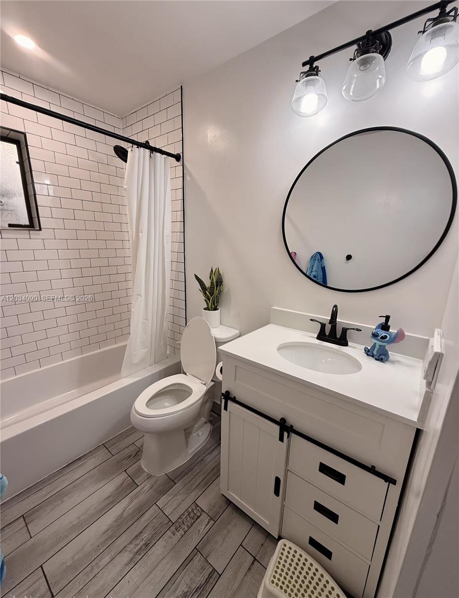 A bathroom features a white vanity, a round mirror, a toilet, and a subway-tiled tub — 8520 SW 133rd Ave Rd # 424, Miami FL 33183, MIAMI, FL
