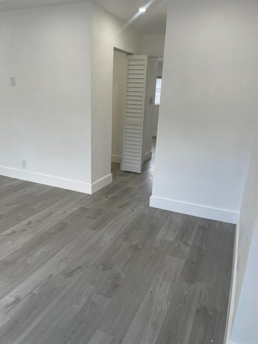 A room with gray wood-look flooring, white walls, white baseboards, and a louvered closet door — 880 NW 8th Avenue, Pompano Beach FL 33060, POMPANO BEACH, FL