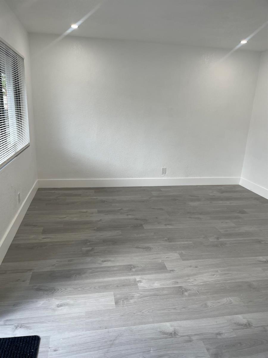 An empty room with white walls, gray wood-look flooring, and a window with blinds — 880 NW 8th Avenue, Pompano Beach FL 33060, POMPANO BEACH, FL