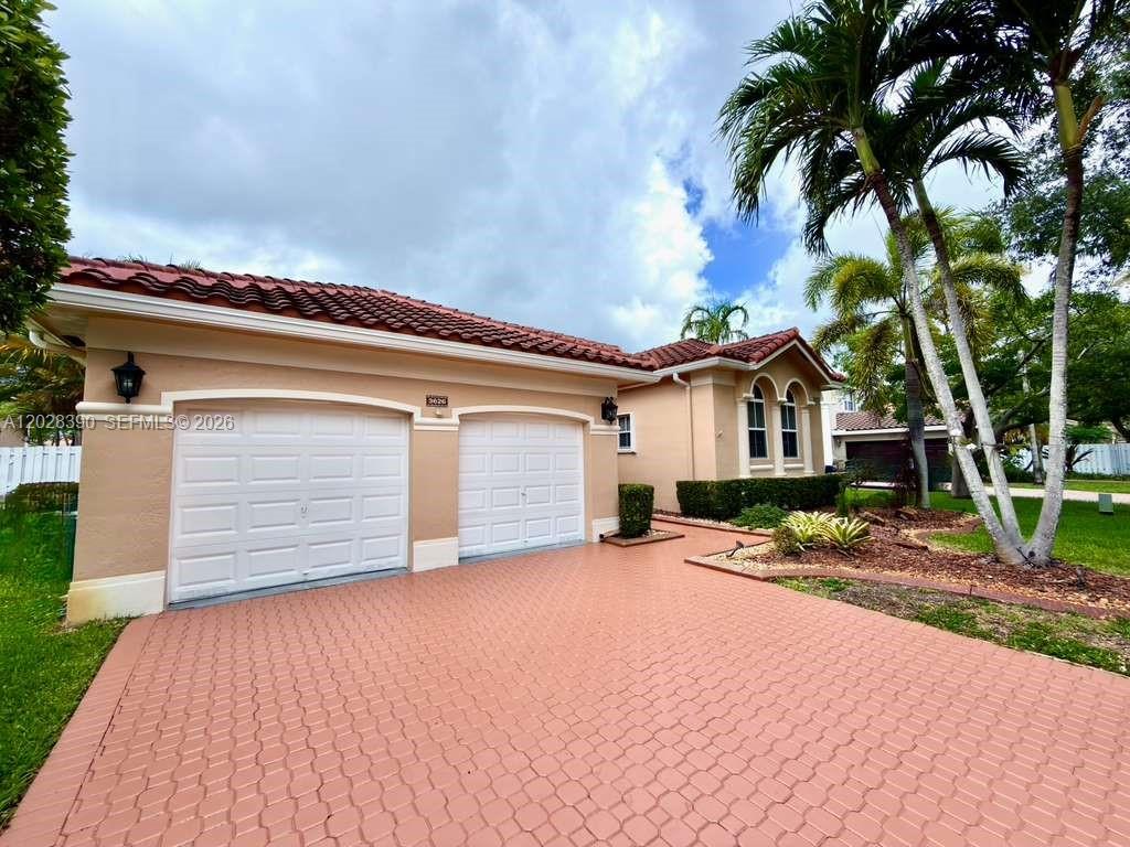 A beige house with a two-car garage and a red-tiled roof features a paved driveway — 3626 SW 161st Ter, Miramar FL 33027, MIRAMAR, FL