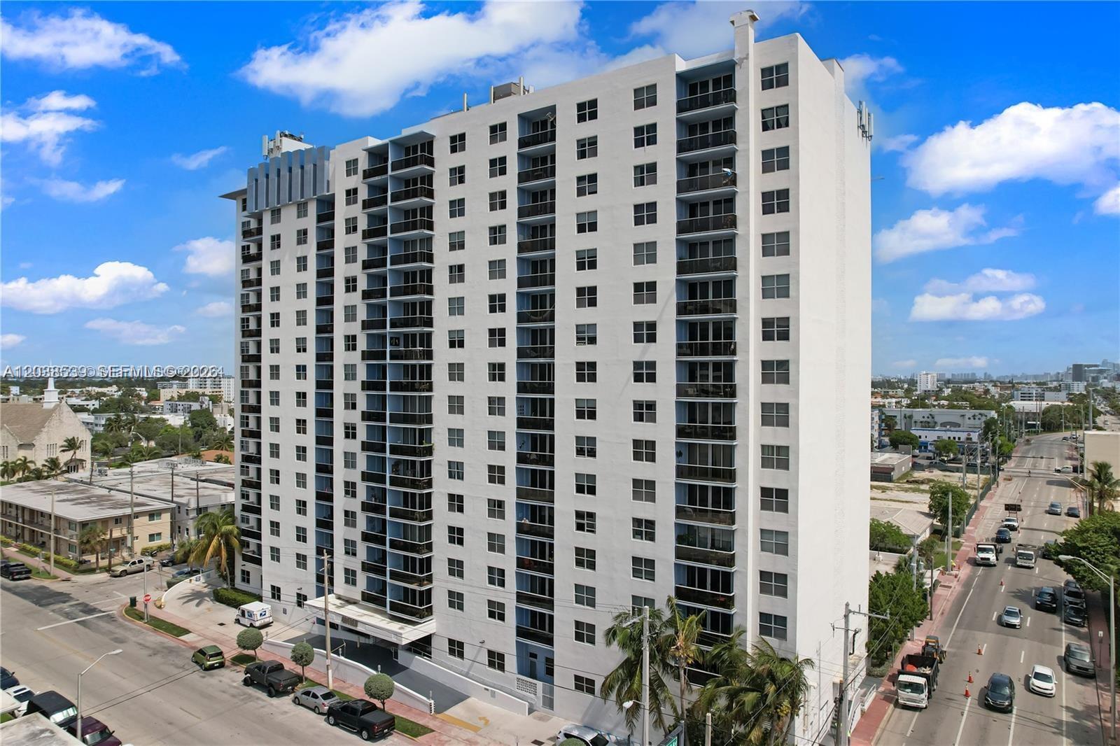 An aerial view shows a tall white residential building with a rooftop pool and parking — 401 69th St, Miami Beach FL 33141, MIAMI BEACH, FL