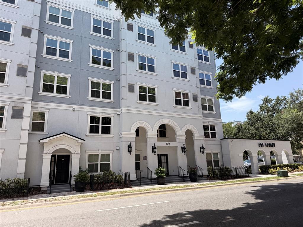 A multi-story apartment building features a light-colored facade with arched entryways and street-level landscaping — 304 E SOUTH STREET UNIT 6028, ORLANDO, FL