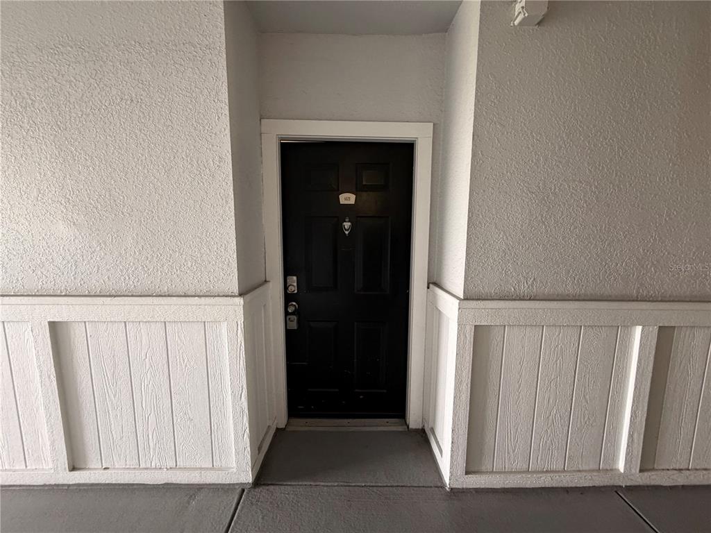 A black front door with a white frame is set between white paneled walls — 304 E SOUTH STREET UNIT 6028, ORLANDO, FL