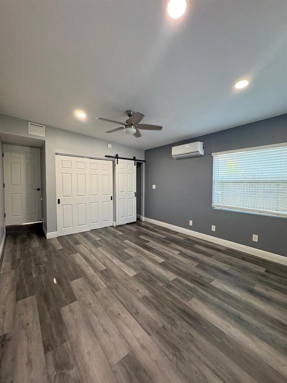 A bedroom features gray walls, wood-look flooring, a ceiling fan, and a sliding barn door — 14347 DELMAR STREET, DADE CITY, FL