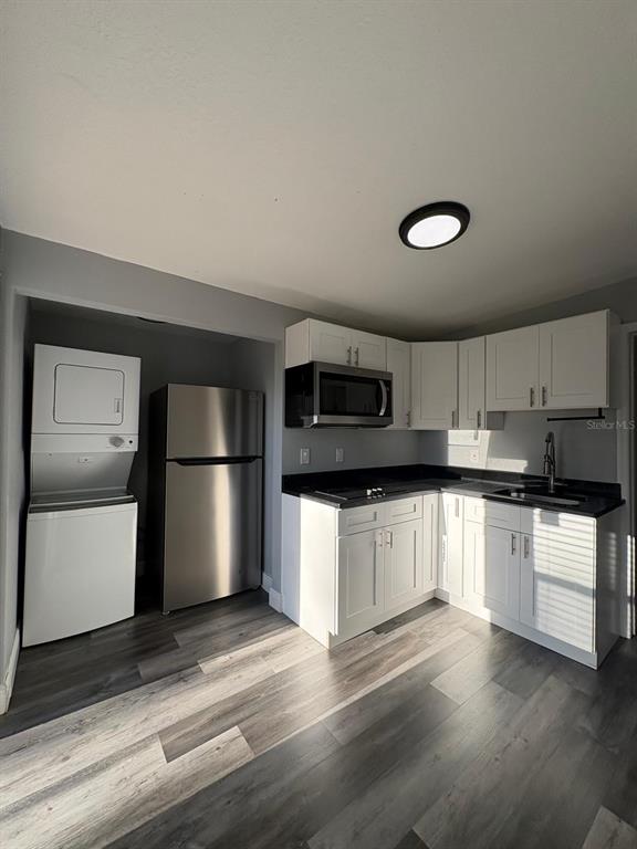 A kitchen features white cabinets, stainless steel appliances, a stacked washer-dryer, and wood-look flooring — 14347 DELMAR STREET, DADE CITY, FL