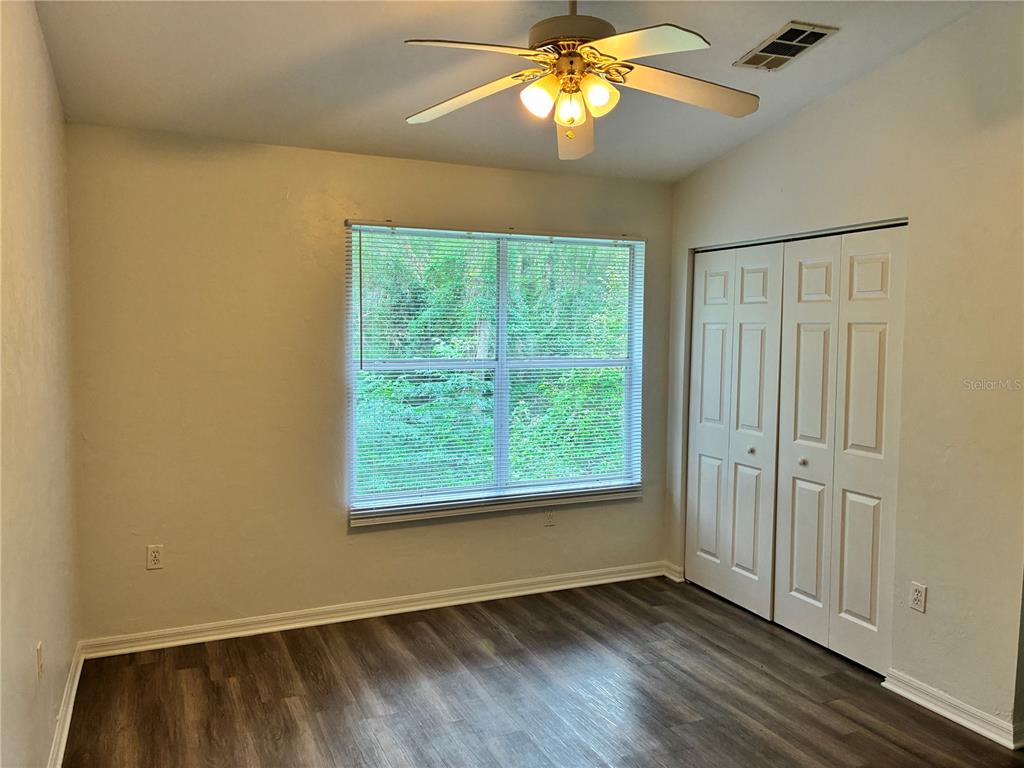 A bedroom with light-colored walls, wood-look flooring, a ceiling fan, and white closet doors — 4415 SW 34TH STREET UNIT 304, GAINESVILLE, FL