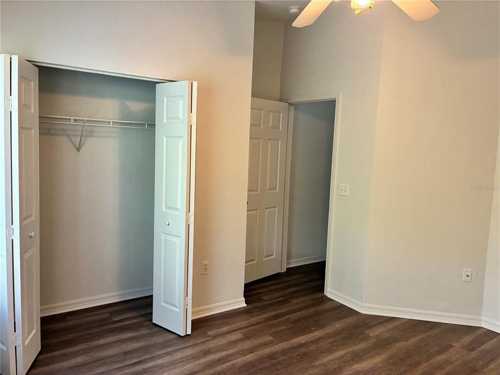 A bedroom features wood-look flooring, a white closet with bi-fold doors, and a doorway — 4415 SW 34TH STREET UNIT 304, GAINESVILLE, FL
