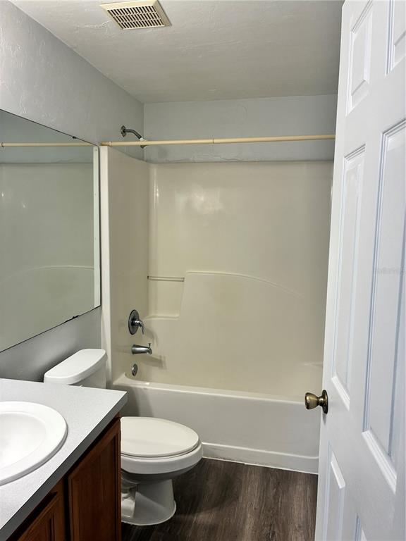A bathroom features a white tub-shower combo, a vanity with a mirror, and wood-look flooring — 4415 SW 34TH STREET UNIT 304, GAINESVILLE, FL
