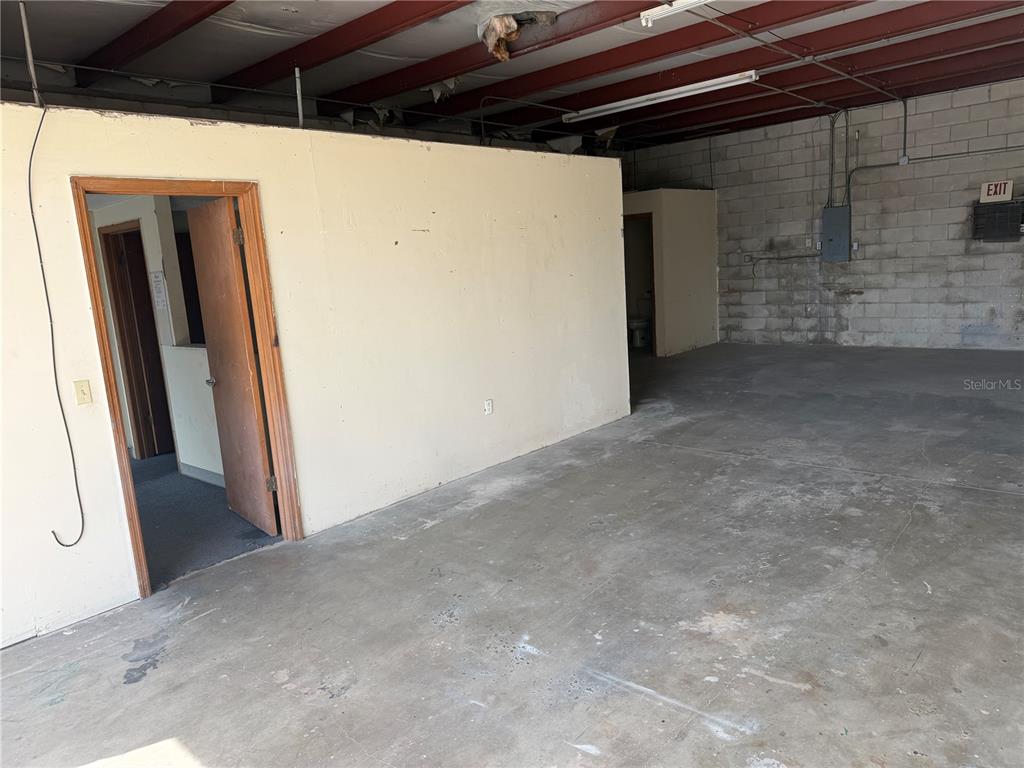 An interior view of a warehouse space featuring a partition wall, two doorways, and concrete floors — 1706 N MAGNOLIA AVENUE UNIT 201, OCALA, FL