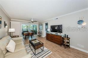 A living room features light wood flooring, a beige sofa, and a television on a dresser — 6294 BAHIA DEL MAR CIRCLE UNIT 103, ST PETERSBURG, FL