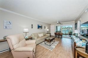 A living room with a beige armchair, sofa, coffee table, and sliding glass doors — 6294 BAHIA DEL MAR CIRCLE UNIT 103, ST PETERSBURG, FL