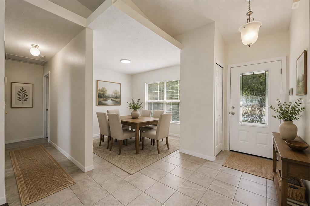 A dining area with a table and chairs sits adjacent to a tiled entryway — 10803 SIENA DRIVE, CLERMONT, FL