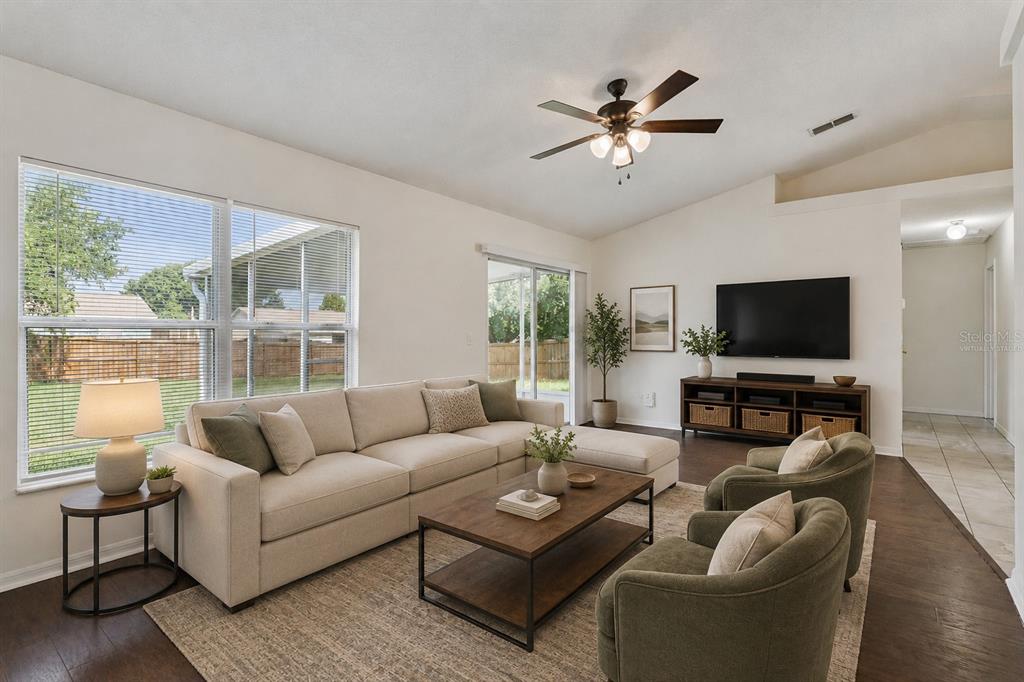 A living room features a beige sectional, two green armchairs, a coffee table, and television — 10803 SIENA DRIVE, CLERMONT, FL