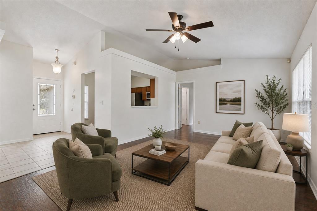 A living room with a beige sofa, two olive armchairs, a coffee table, and wood flooring — 10803 SIENA DRIVE, CLERMONT, FL