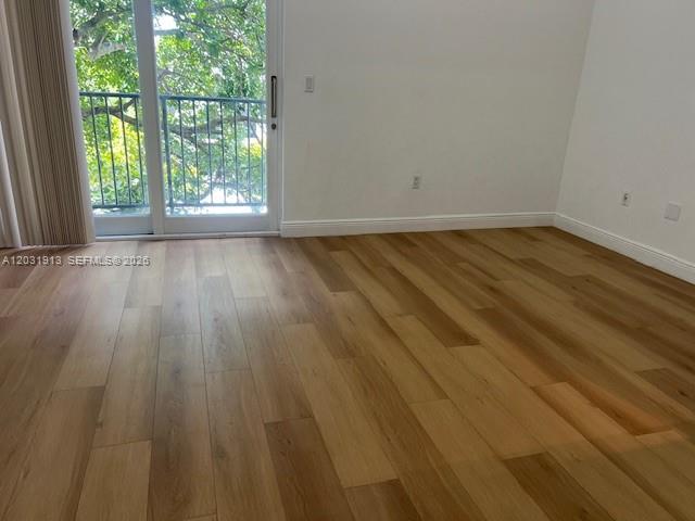 An empty room features light wood-look flooring, white walls, and a sliding glass door — 2701 SW 3rd Ave # 302, Miami FL 33129, MIAMI, FL