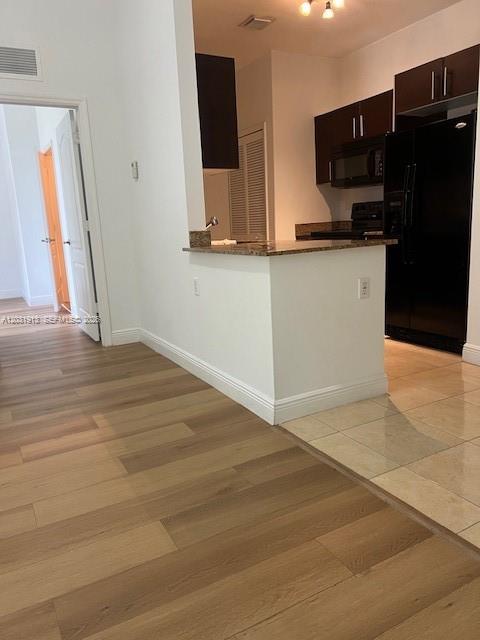 A kitchen with dark cabinets and a breakfast bar opens to a wood-floored hallway — 2701 SW 3rd Ave # 302, Miami FL 33129, MIAMI, FL