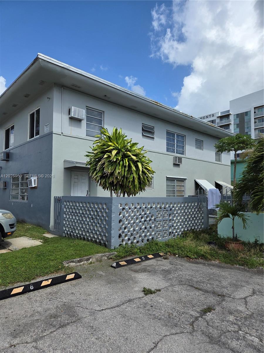 A two-story apartment building features a grey exterior, a decorative concrete wall, and parking spaces — 511 NE 82nd Ter, Miami FL 33138, MIAMI, FL