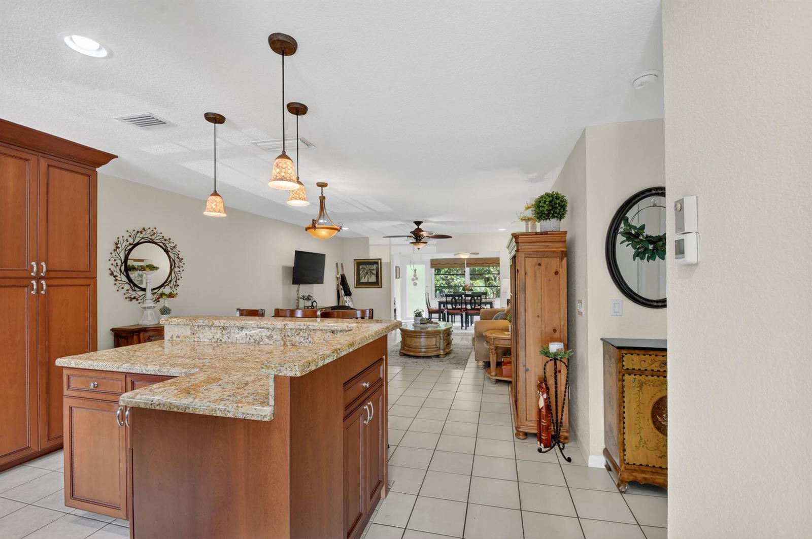 A kitchen island with granite countertops sits in an open-concept home with tile flooring — 300 Cape Cod Circle, Lake Worth FL 33467, LAKE WORTH, FL