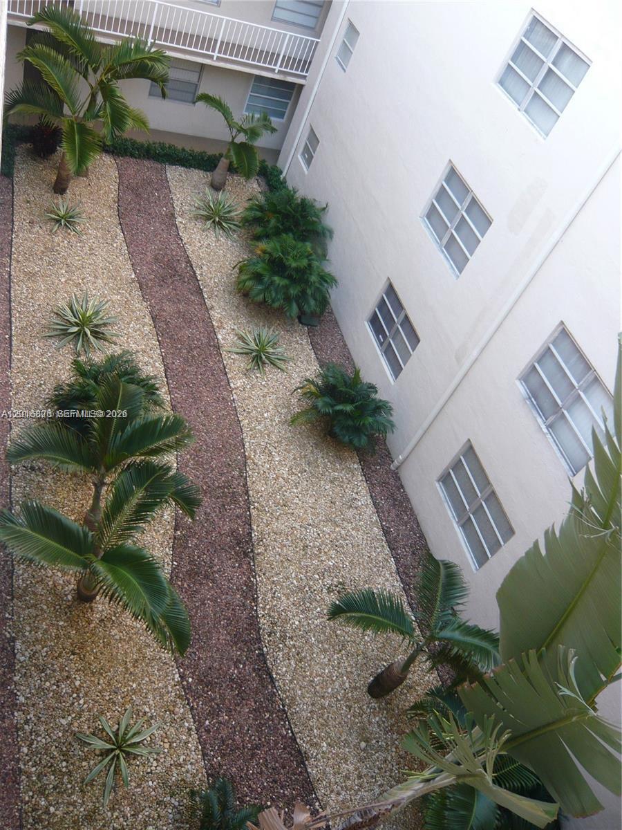 An aerial view shows a landscaped courtyard with gravel paths, palm trees, and building windows — 7715 SW 86th St # 405, Miami FL 33143, MIAMI, FL