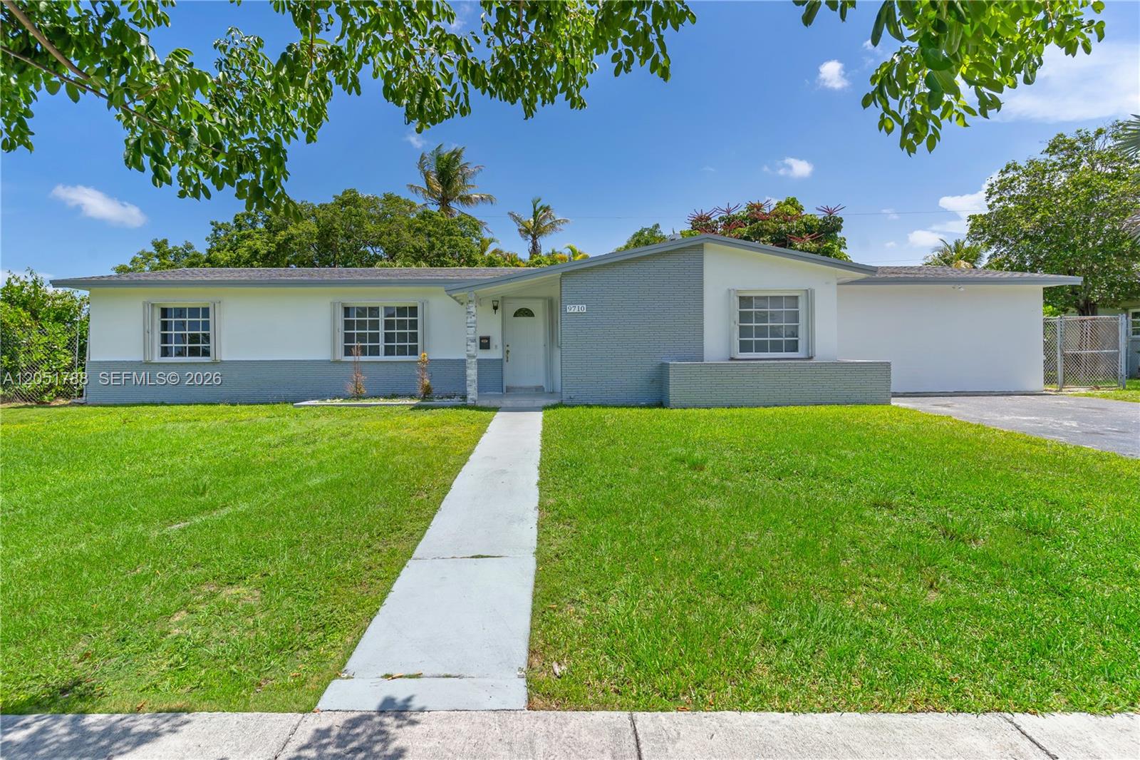 A single-story house with a gray and white exterior features a front lawn and walkway — 9710 SW 159th St, Miami FL 33157, MIAMI, FL