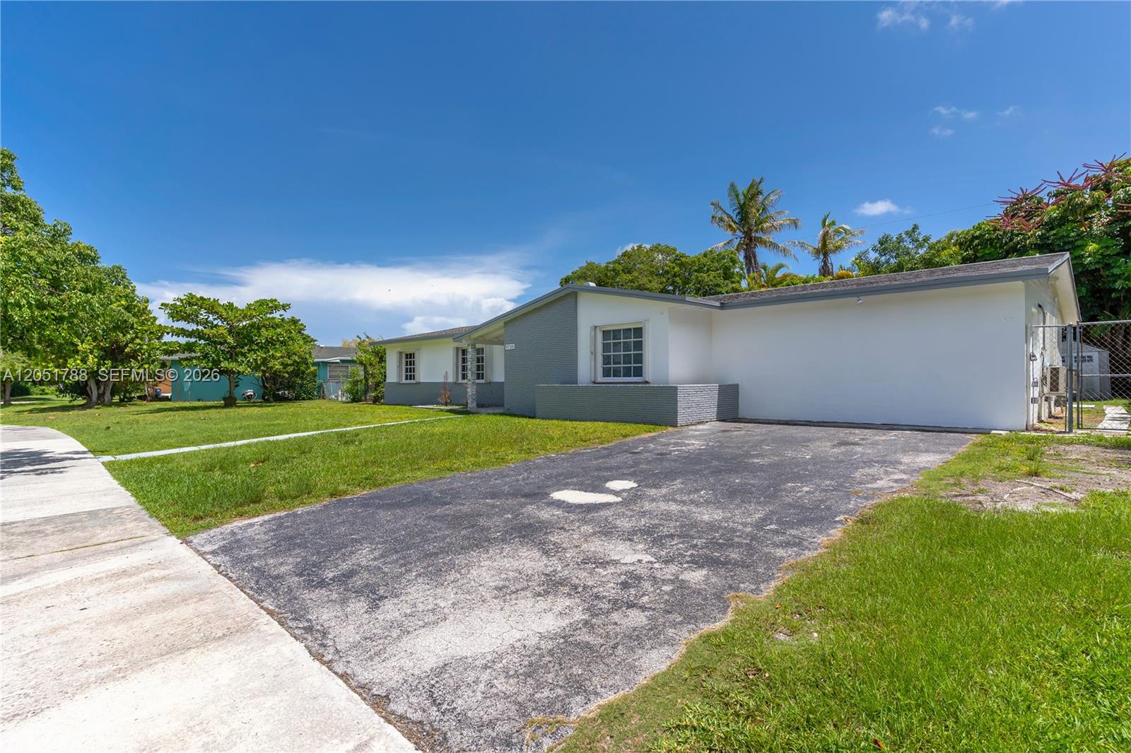 A single-story house with a white and gray exterior features a paved driveway and lawn — 9710 SW 159th St, Miami FL 33157, MIAMI, FL