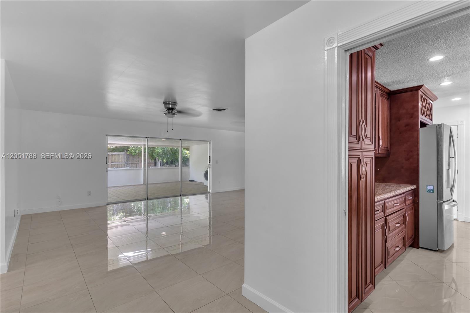 A view from a doorway looking into a tiled living area and a kitchen — 9710 SW 159th St, Miami FL 33157, MIAMI, FL