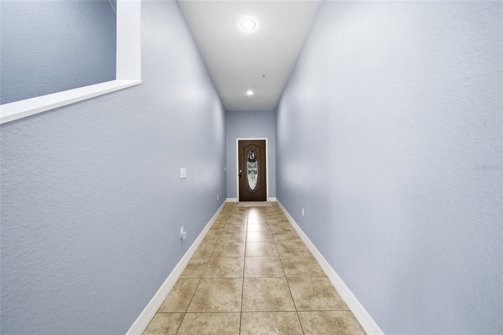 A long entryway features light blue walls, tile flooring, and a dark wood front door — 515 VILLA TREVISO COURT, APOLLO BEACH, FL
