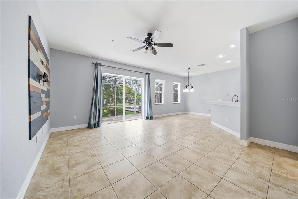 An open-concept living and dining area features light tile flooring, gray walls, and sliding doors — 515 VILLA TREVISO COURT, APOLLO BEACH, FL