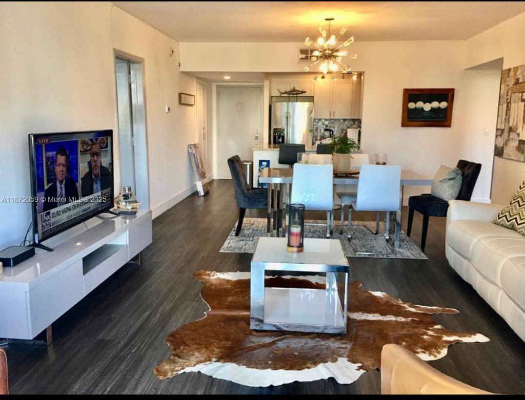 A living and dining area features dark wood floors, a cowhide rug, and modern furniture — 11111 Biscayne Blvd # 4D, Miami FL 33181, MIAMI, FL
