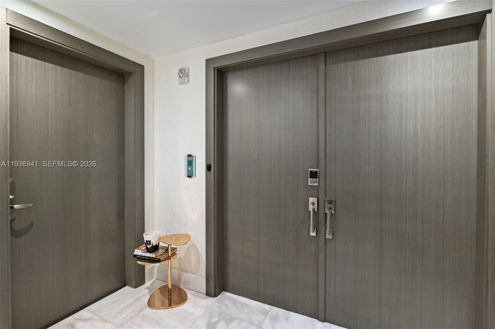 A hallway features two gray wood-grain doors, white marble flooring, and a small gold side table — 1331 Brickell Bay Dr # 2907, Miami FL 33131, MIAMI, FL