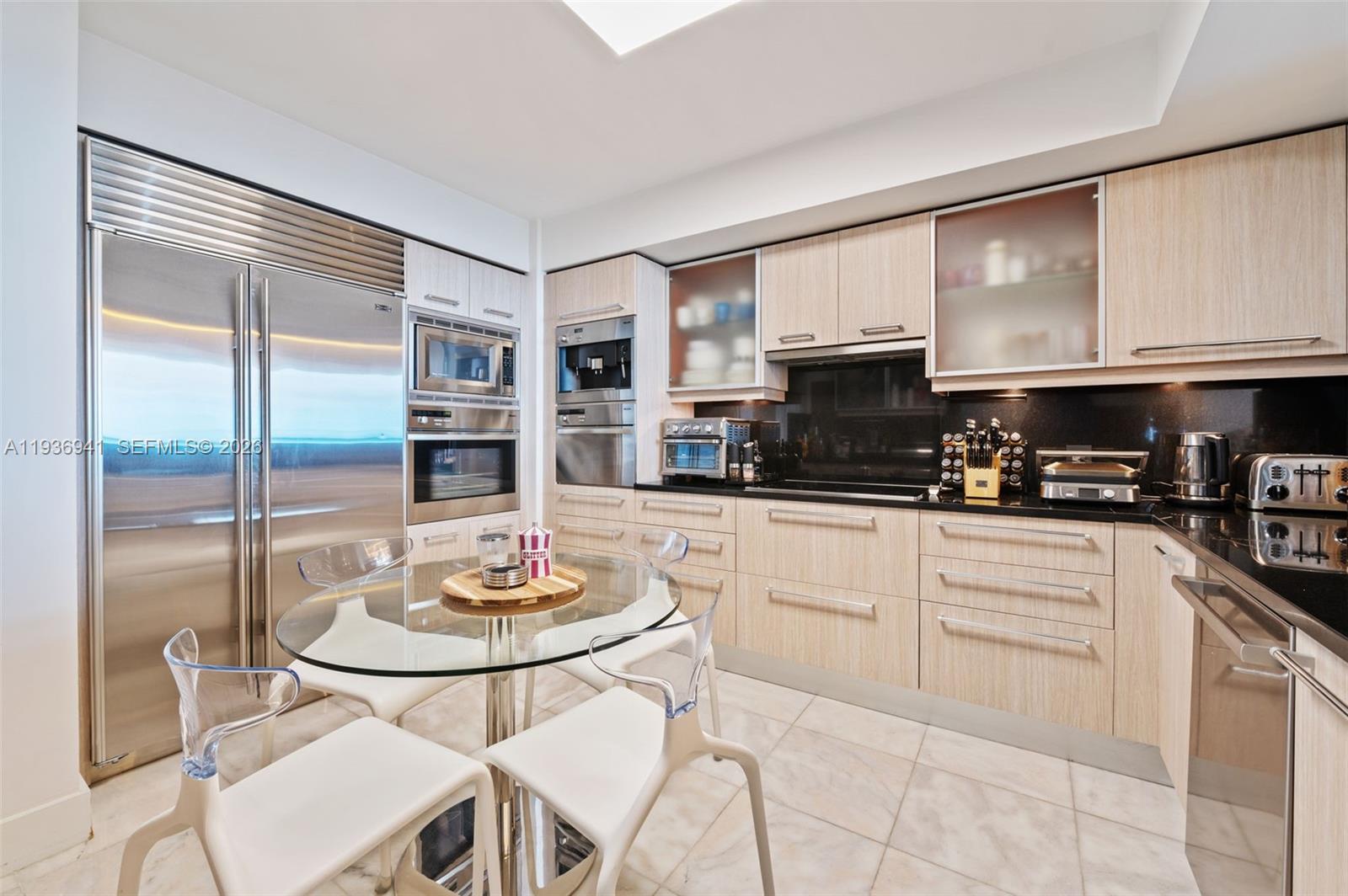 A modern kitchen features light wood cabinetry, stainless steel appliances, and a glass dining table — 1331 Brickell Bay Dr # 2907, Miami FL 33131, MIAMI, FL