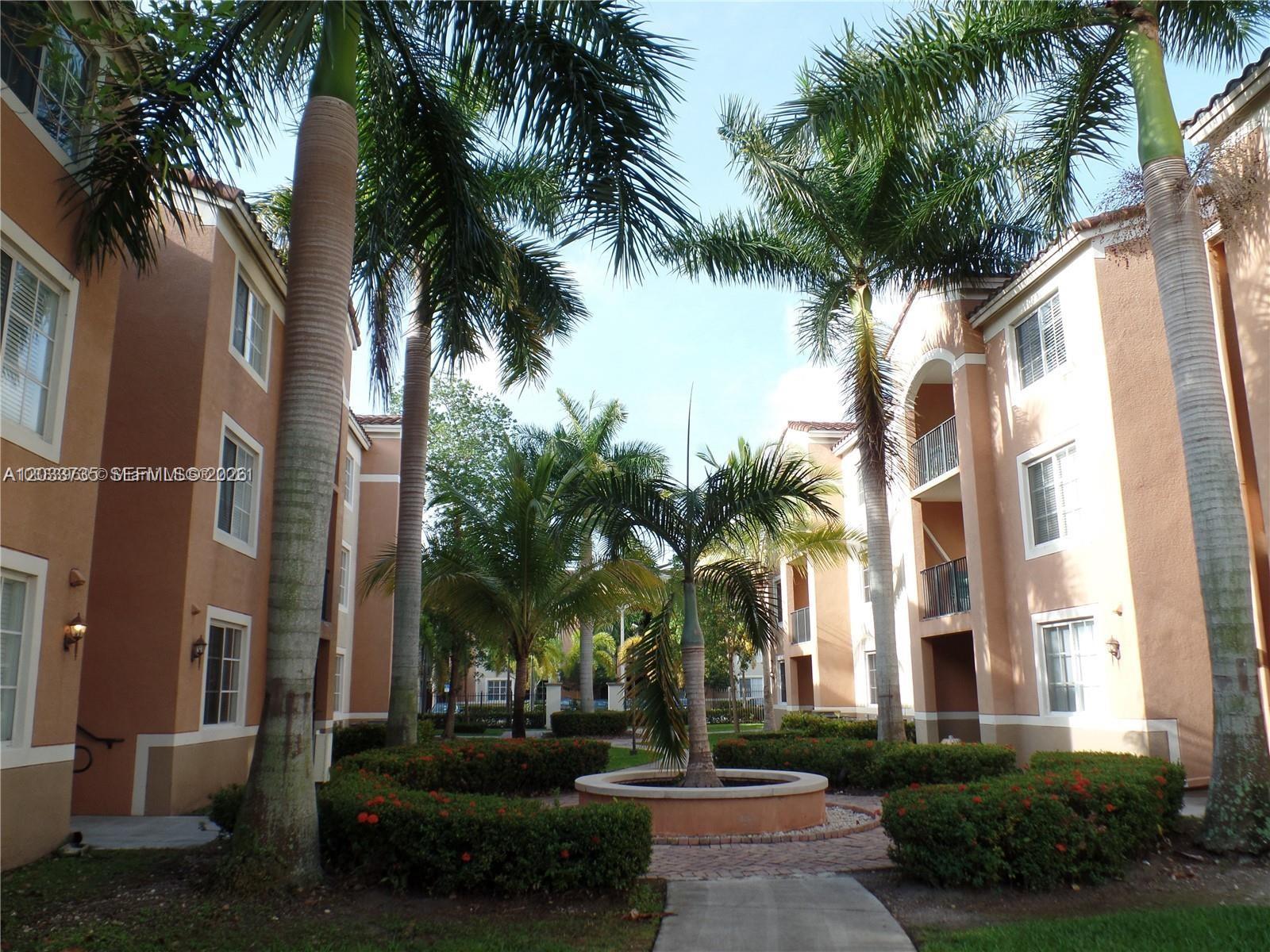 An exterior view of a courtyard between two apartment buildings with palm trees and landscaping — 6801 SW 44th St # 203, Miami FL 33155, MIAMI, FL