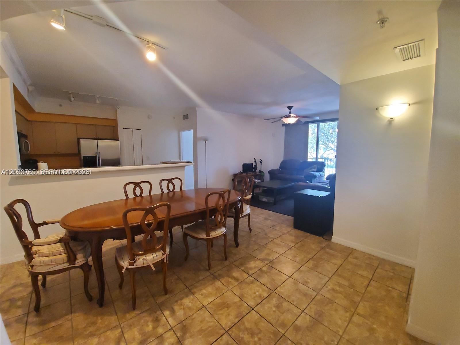 A dining area with a wooden table and chairs opens into a living room — 6801 SW 44th St # 203, Miami FL 33155, MIAMI, FL