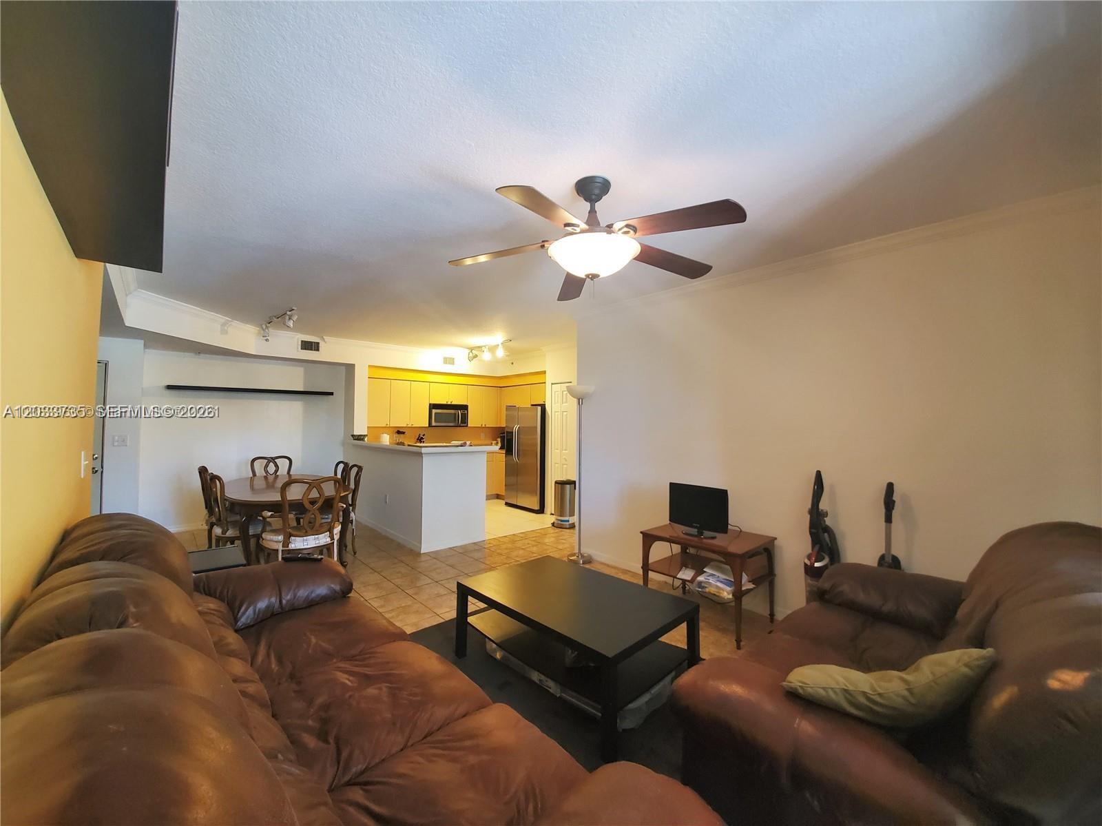 A living room with brown leather sofas, a coffee table, and an open kitchen area — 6801 SW 44th St # 203, Miami FL 33155, MIAMI, FL