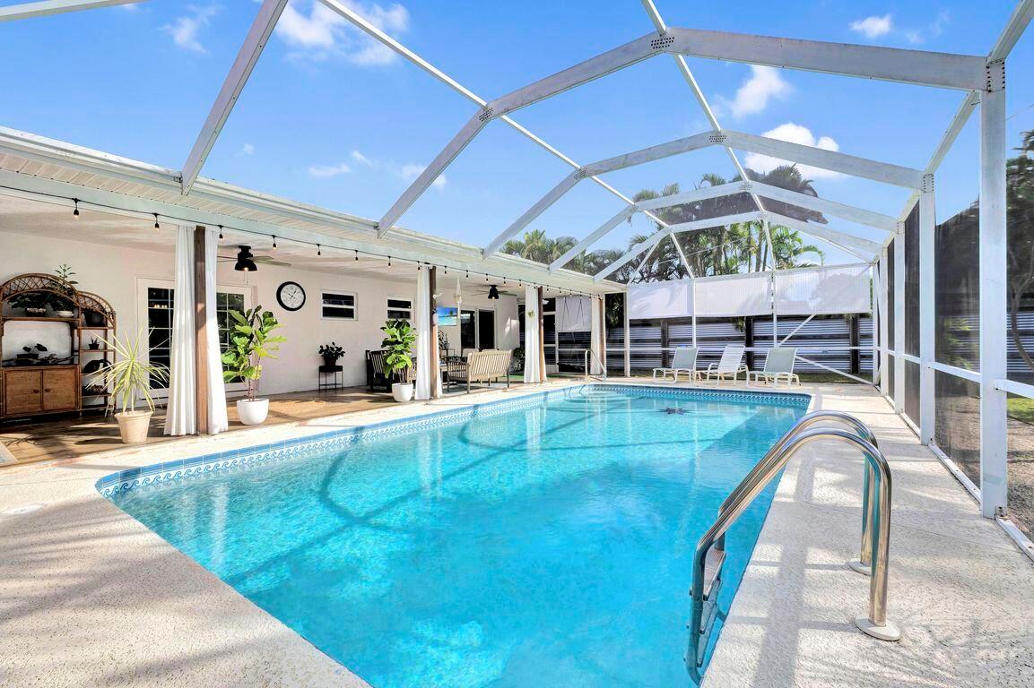 A screened-in patio features a swimming pool, lounge chairs, and a covered seating area — 1104 NW 12th Terrace, Stuart FL 34994, STUART, FL