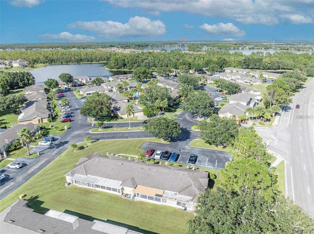 An aerial view shows a residential complex with multiple buildings, parking lots, and a lake — 3125 SANDY SHORE LANE, KISSIMMEE, FL