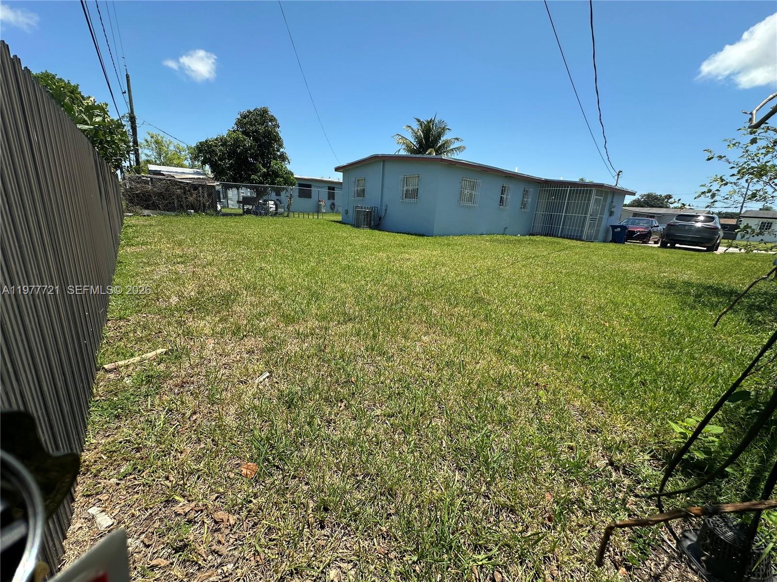 A blue house with security bars on the windows sits on a large grassy lot — 10761 SW 221st St, Miami FL 33170, MIAMI, FL